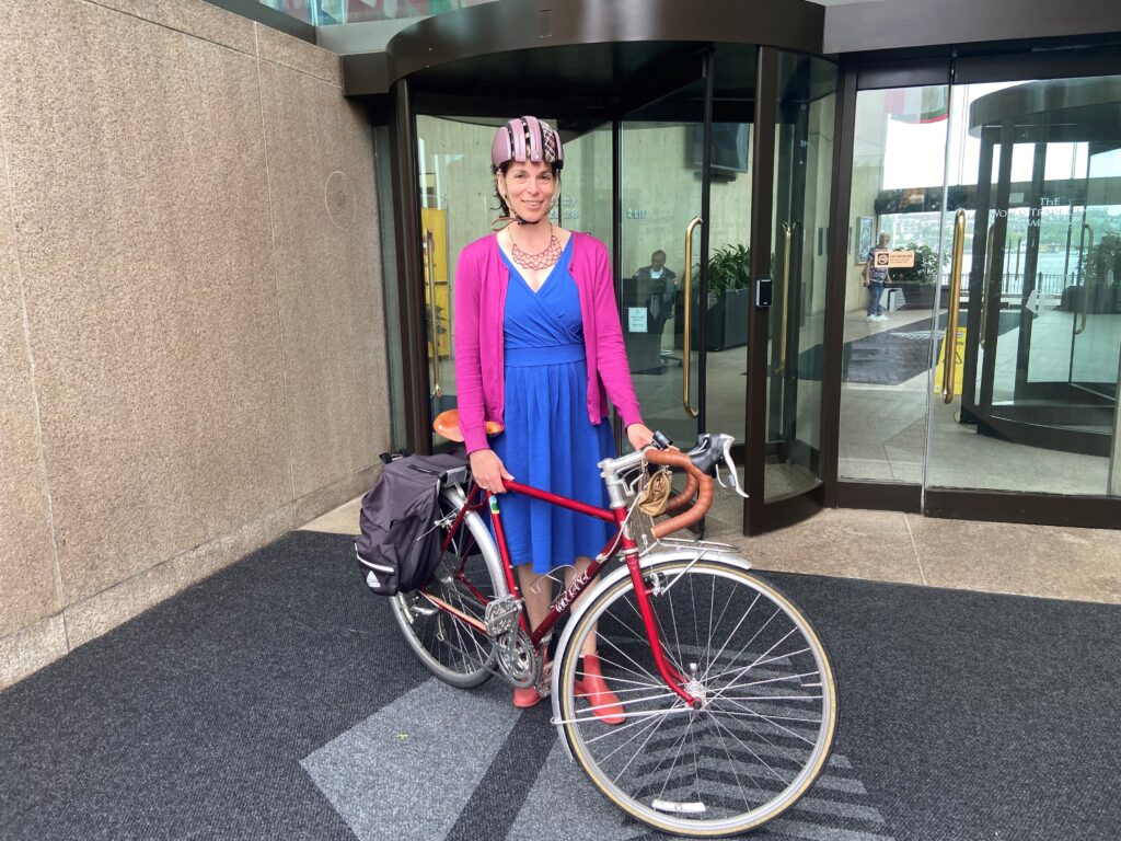 Rochelle with bicycle near office door