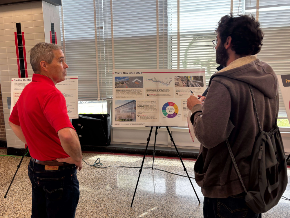 Red Line staff member discussing the project board with a community member
